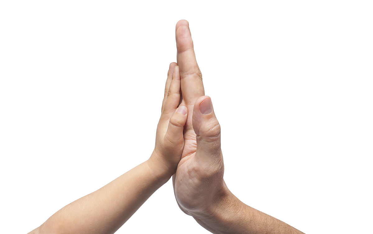 eine Kinder- und eine Erwachsenenhand geben sich High-Five