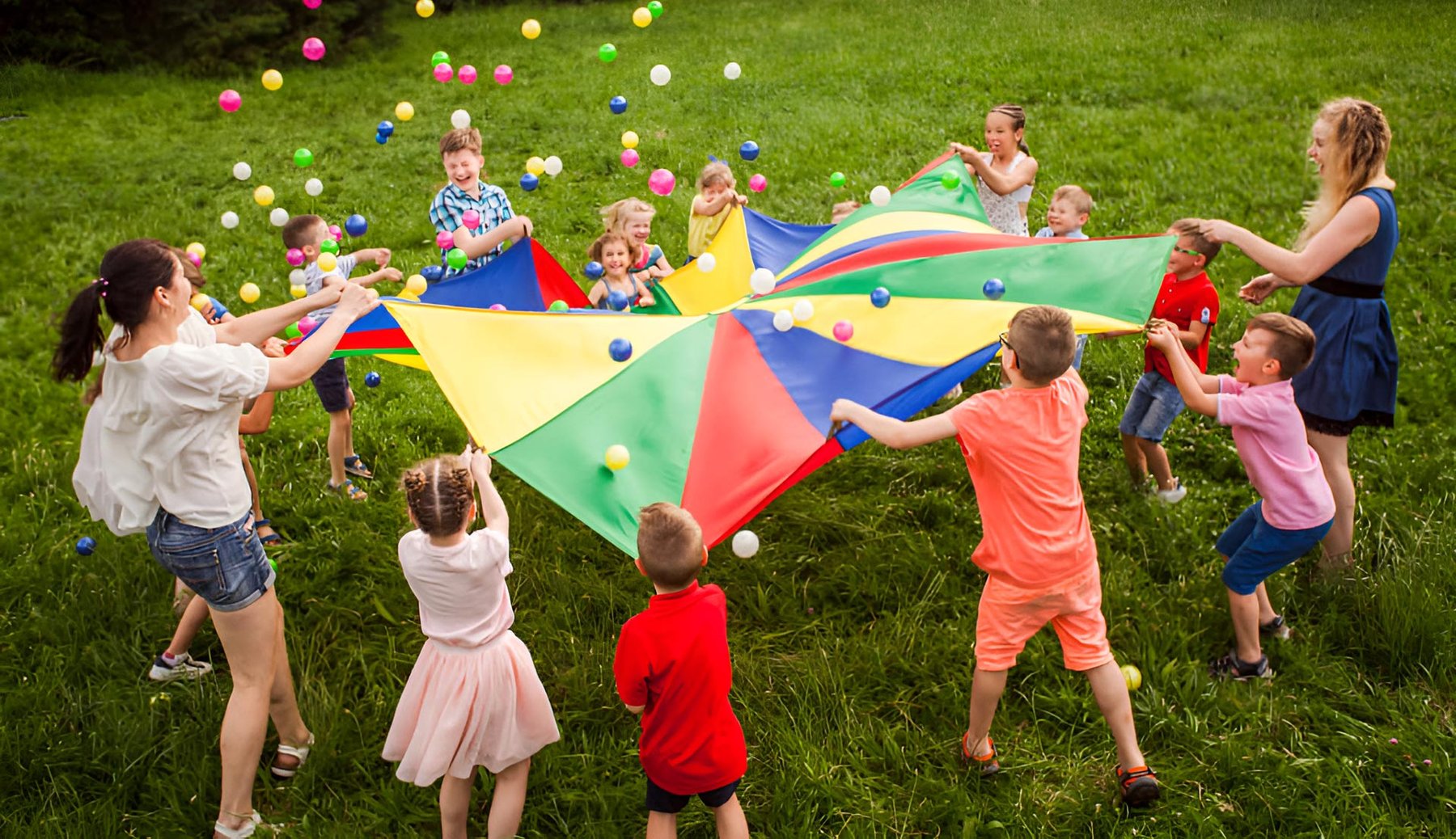 Kinder spielen mit farbigem Schwungtuch im KitaGarten in MV