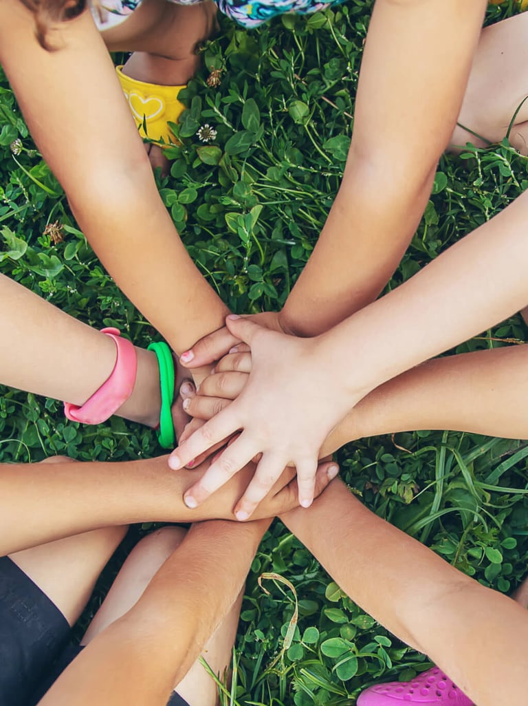Kinderhände in Gemeinschaft auf Gras symbolisiert ILL MV und frühkindliche Bildung MV