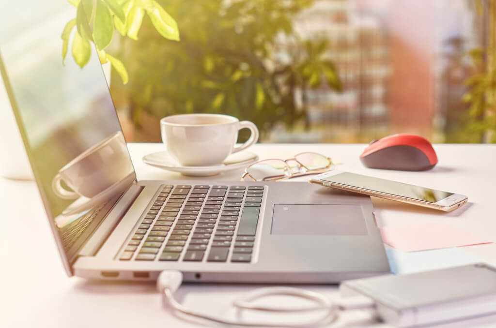 Laptop mit Smartphone Kaffeetasse und Maus auf einem Schreibtisch im Freien