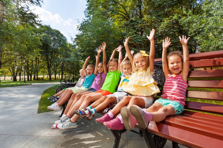 Kinder in einem Park auf einer Bank fröhlich die Arme hoch symbolisiert Kita Spaß und Gemeinschaft ideal für Kitas in MV