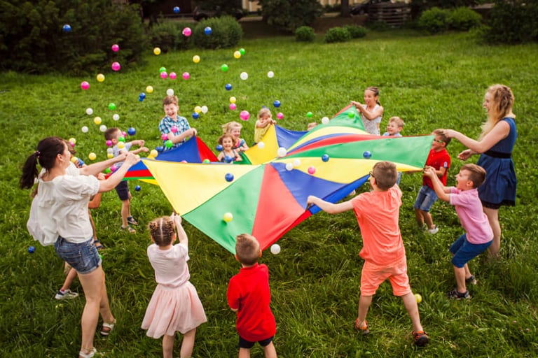 Kinder spielen mit farbigem Schwungtuch im KitaGarten in MV
